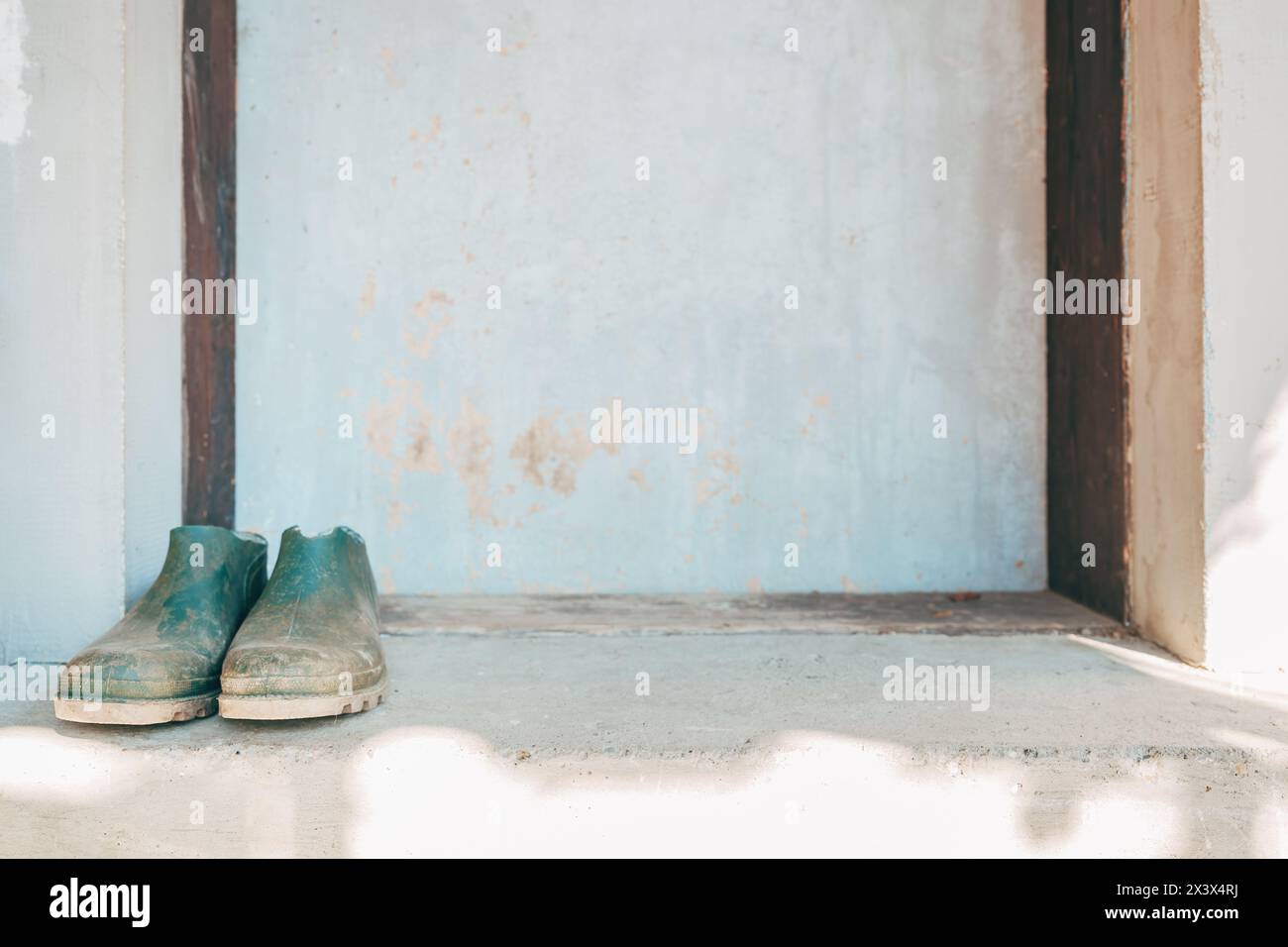 Old farming rubber boots in front of the door, selective focus Stock Photo