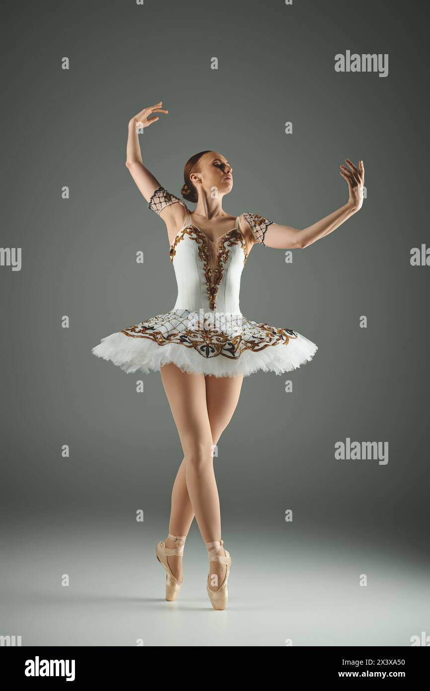 A young beautiful ballerina gracefully performs in a stunning white and gold ballet outfit. Stock Photo