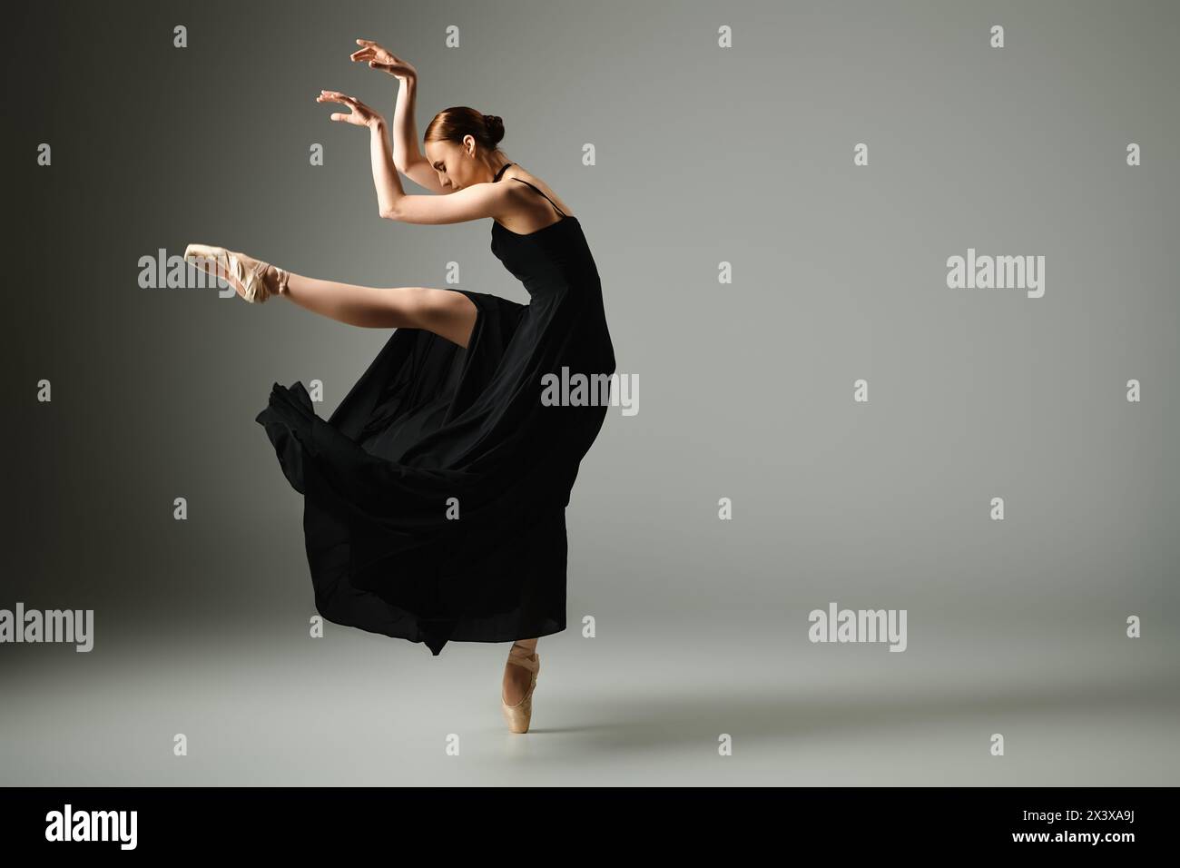 A young, beautiful ballerina in a black dress dances elegantly. Stock Photo