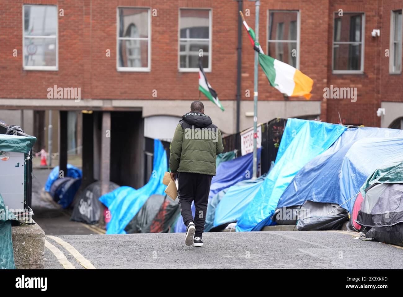 People walking past tents housing asylum seekers near to the