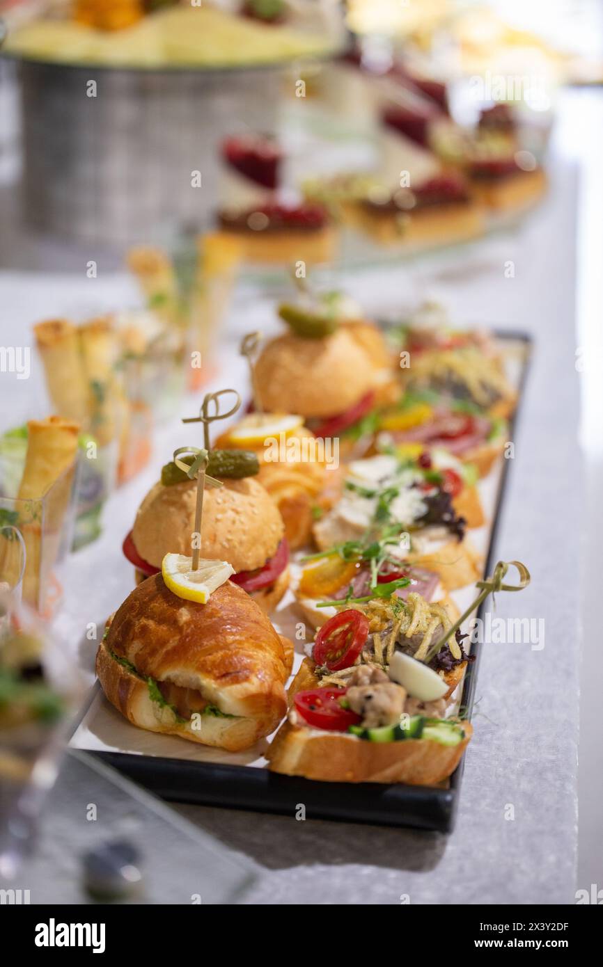 A delicious assortment of freshly baked croissants and gourmet sandwiches beautifully displayed on a platter for a catered event. Stock Photo