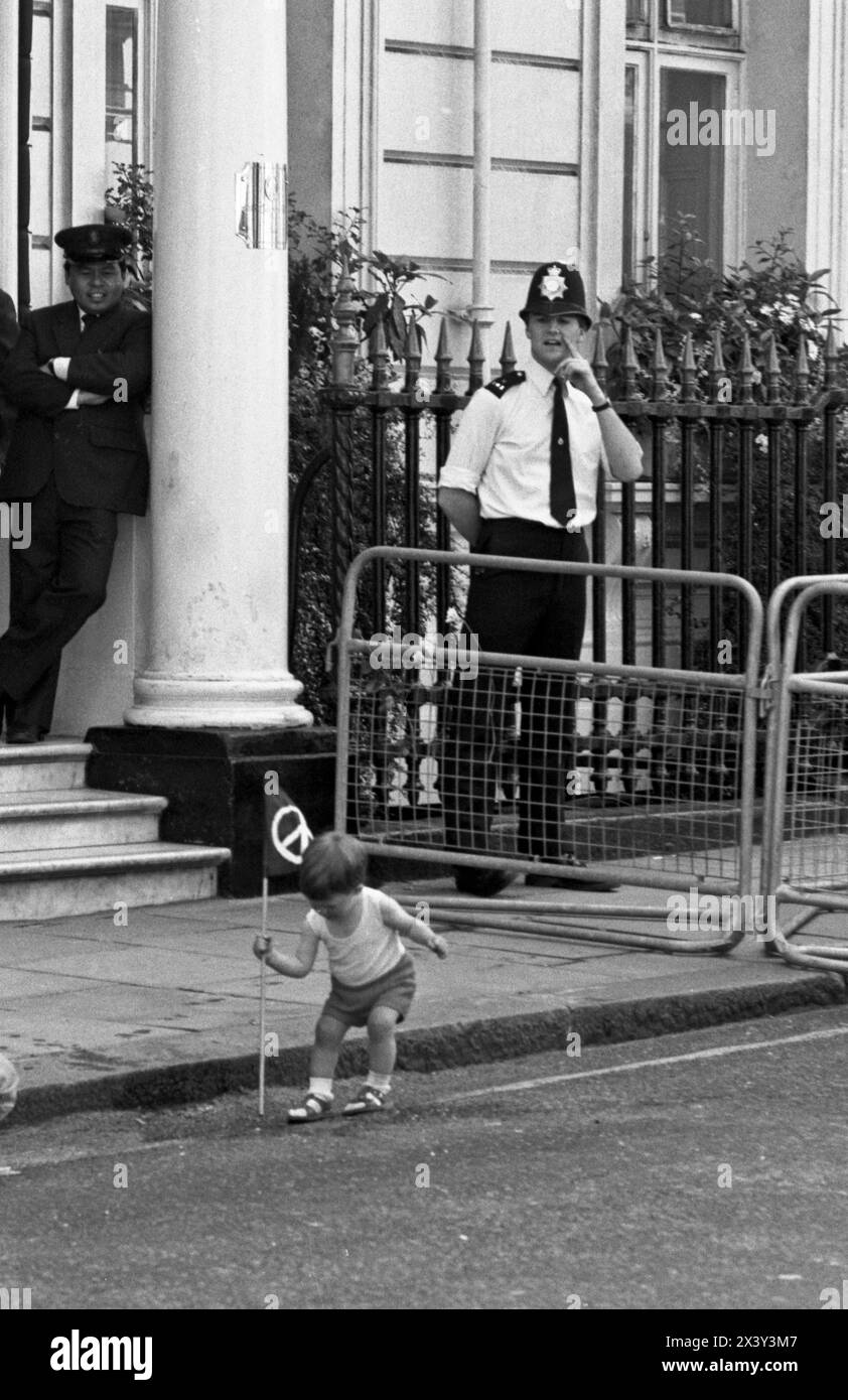 London, UK. 9th June 1984. A child plays with a CND flag in front of a police officer during Grosvenor Square direct action blockade demonstration against Cruise missile deployment, London, UK. 9th June 1984  The non-violent, direct action protest  was in response to American President, Ronald Reagan's visit to the World Economic Summit in London and the deployment of US Cruise missiles in the UK.   The protest coincided with CND's anti Cruise missile rally in Trafalgar Square. London. Grosvenor Square was the location of the American Embassy in the UK at the time of the protest. Stock Photo
