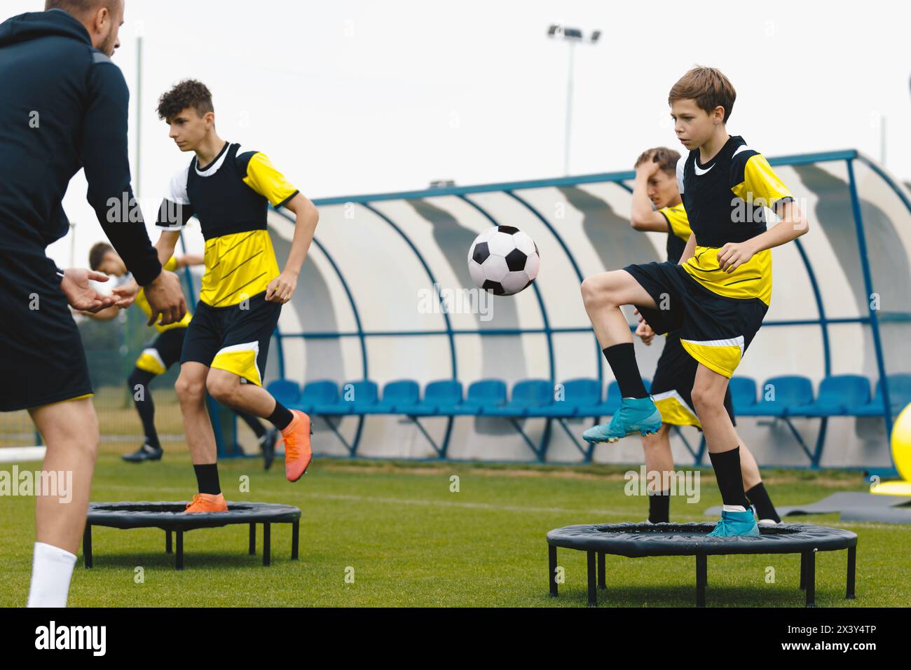 Group of young boys in sports soccer club practicing on jumping trampoline. Teenagers on football training trampoline. Youth athletes improving stabil Stock Photo