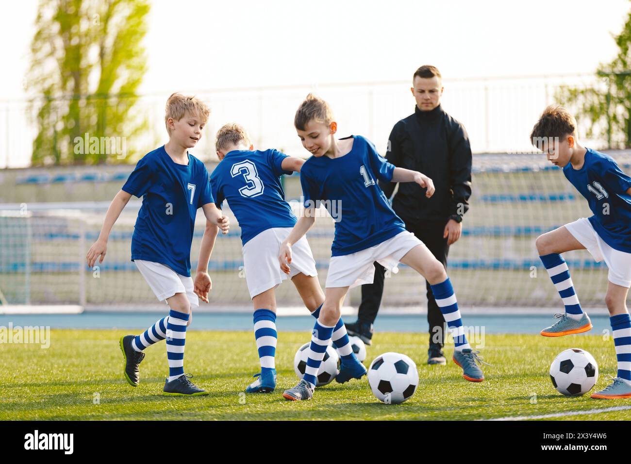 Children Training Football. Young Boys Running with Ball on Training Practice Session. Happy Boys Playing Sports and Having Fun Outdoor Stock Photo