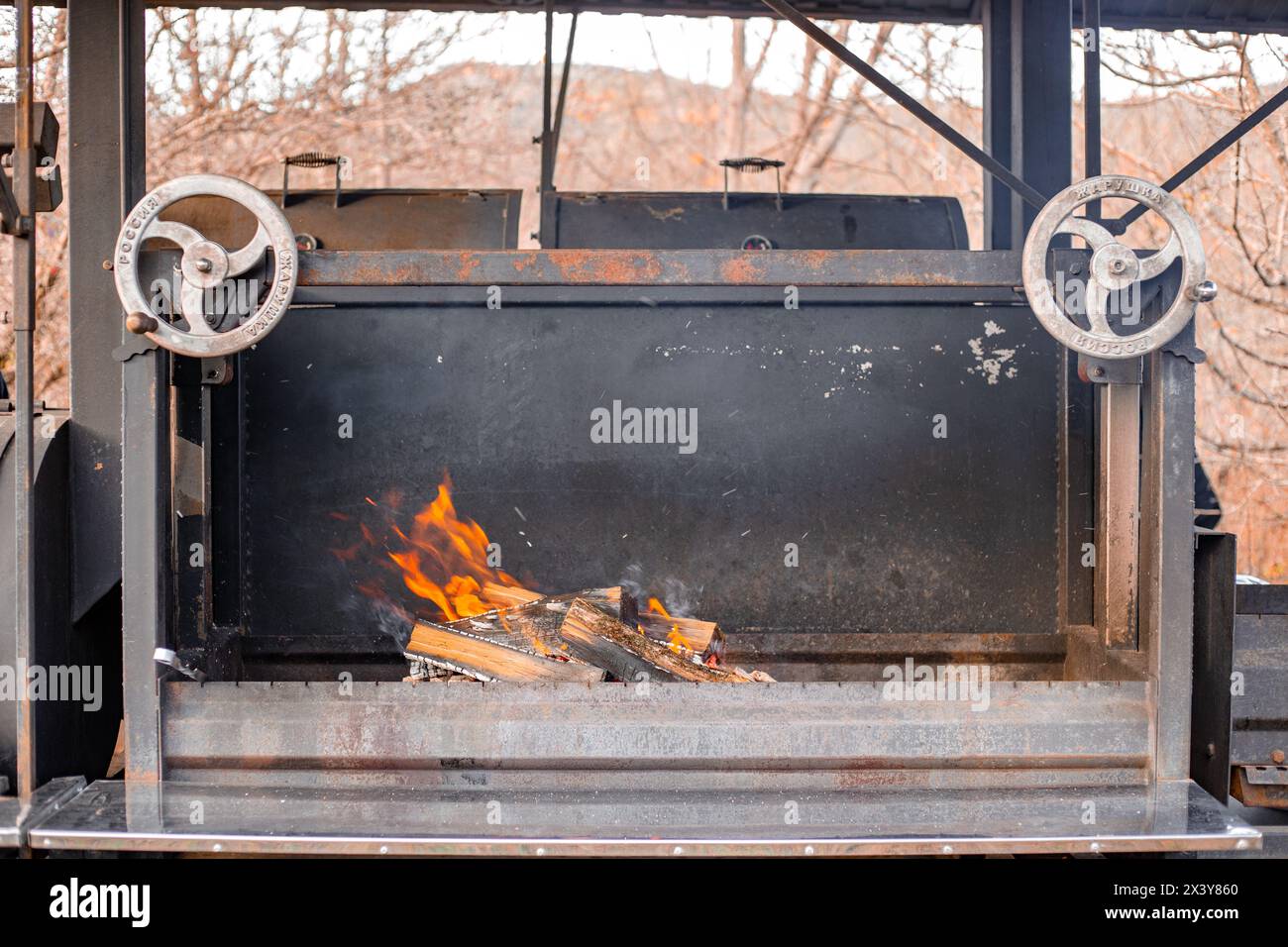 a huge professional barbecue with burning wood. Equipment for barbecue preparation. Stock Photo