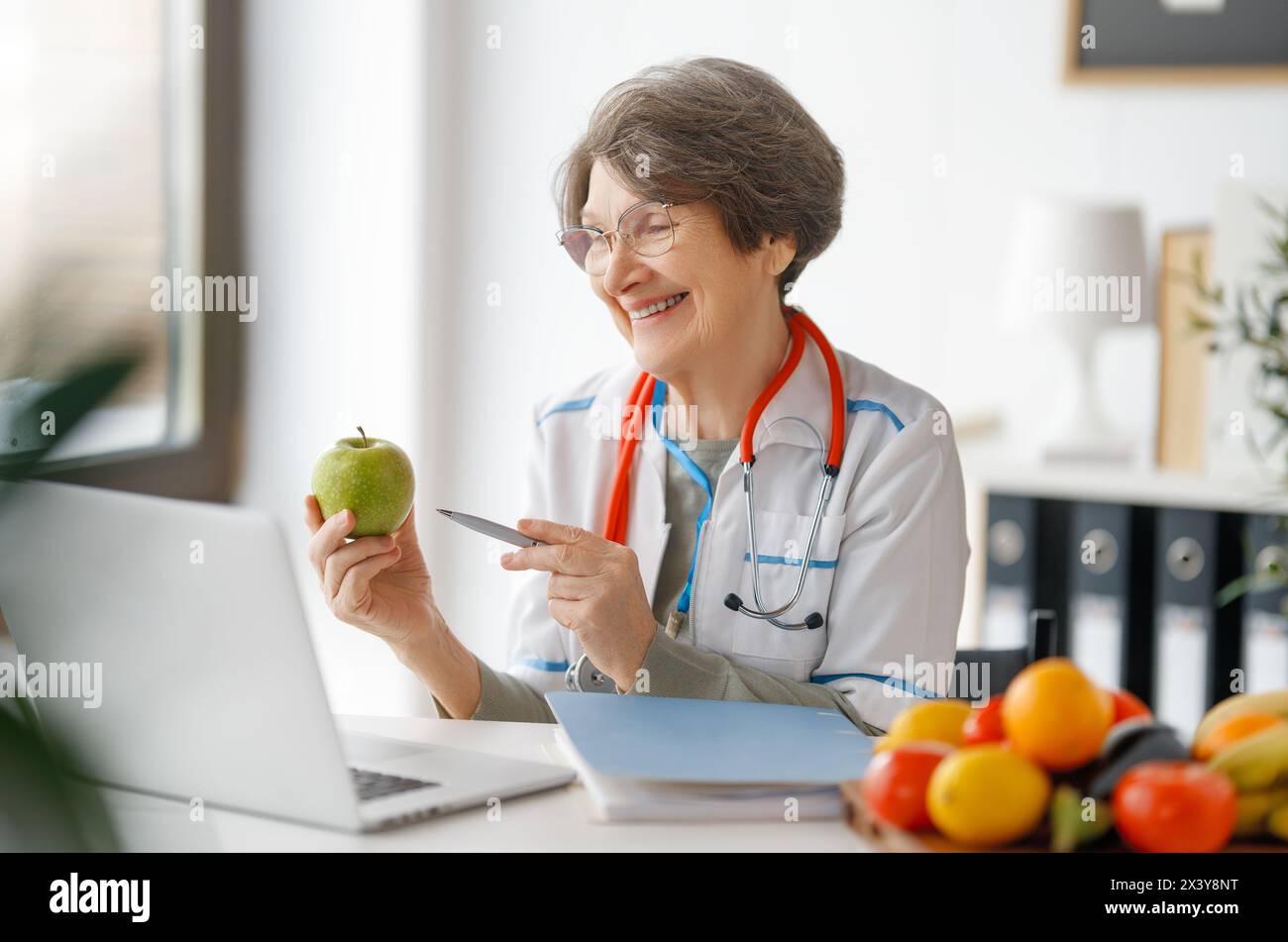 Happy doctor is talking with somebody by laptop. Woman is working in medicine office. Stock Photo