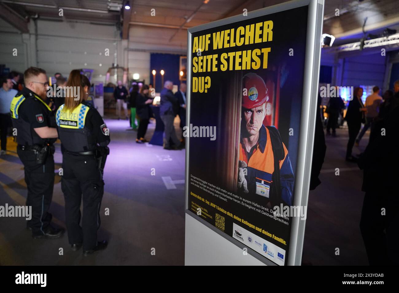 Hamburg, Germany. 29th Apr, 2024. Police officer stands next to a poster from the awareness campaign for port employees in the fight against international drug-related crime with the inscription 'Which side are you on?'. The security authorities presented the new awareness campaign on Monday. Credit: Marcus Brandt/dpa/Alamy Live News Stock Photo