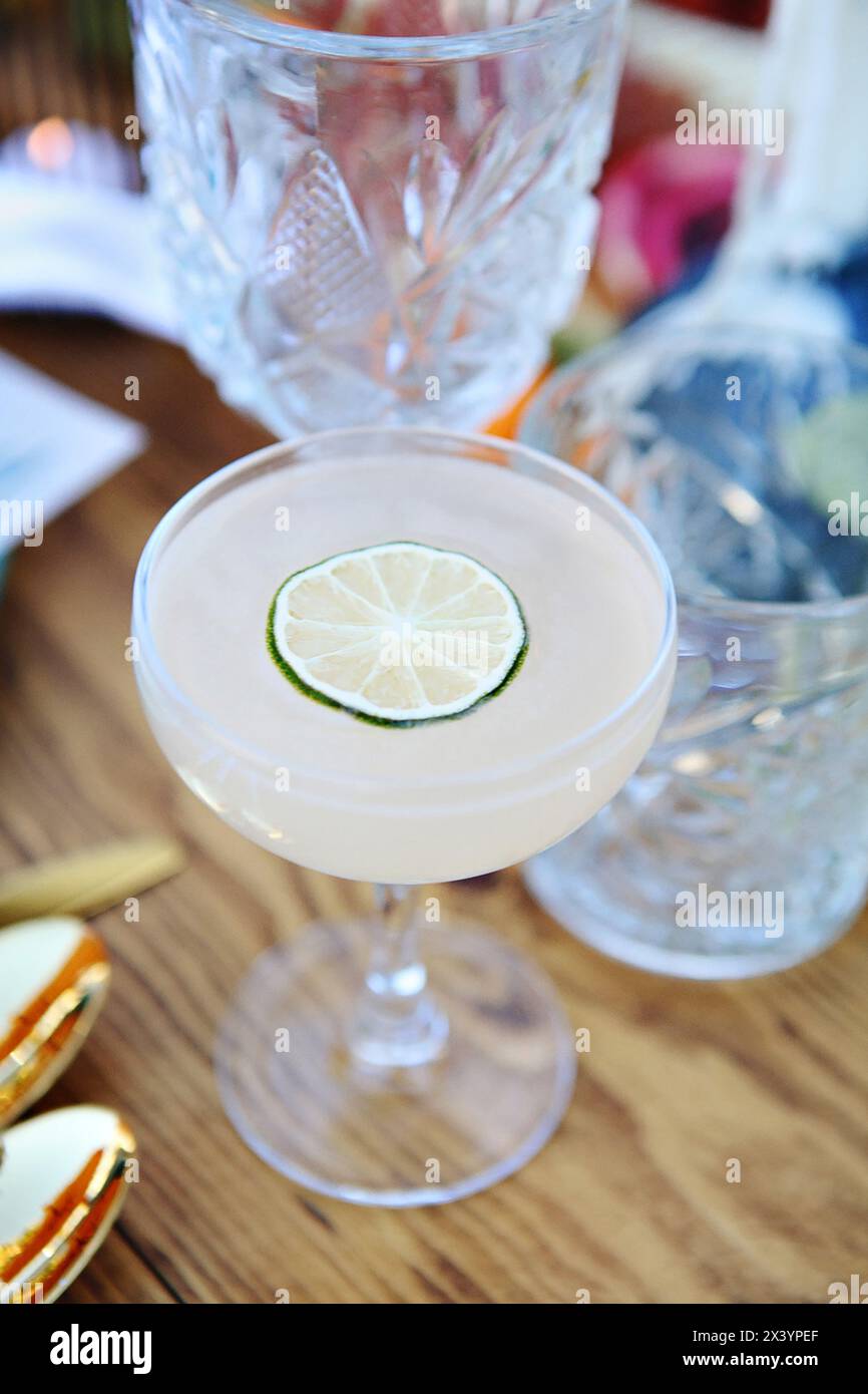 Elegant frothy cocktail topped with a thin lime wheel. Stock Photo
