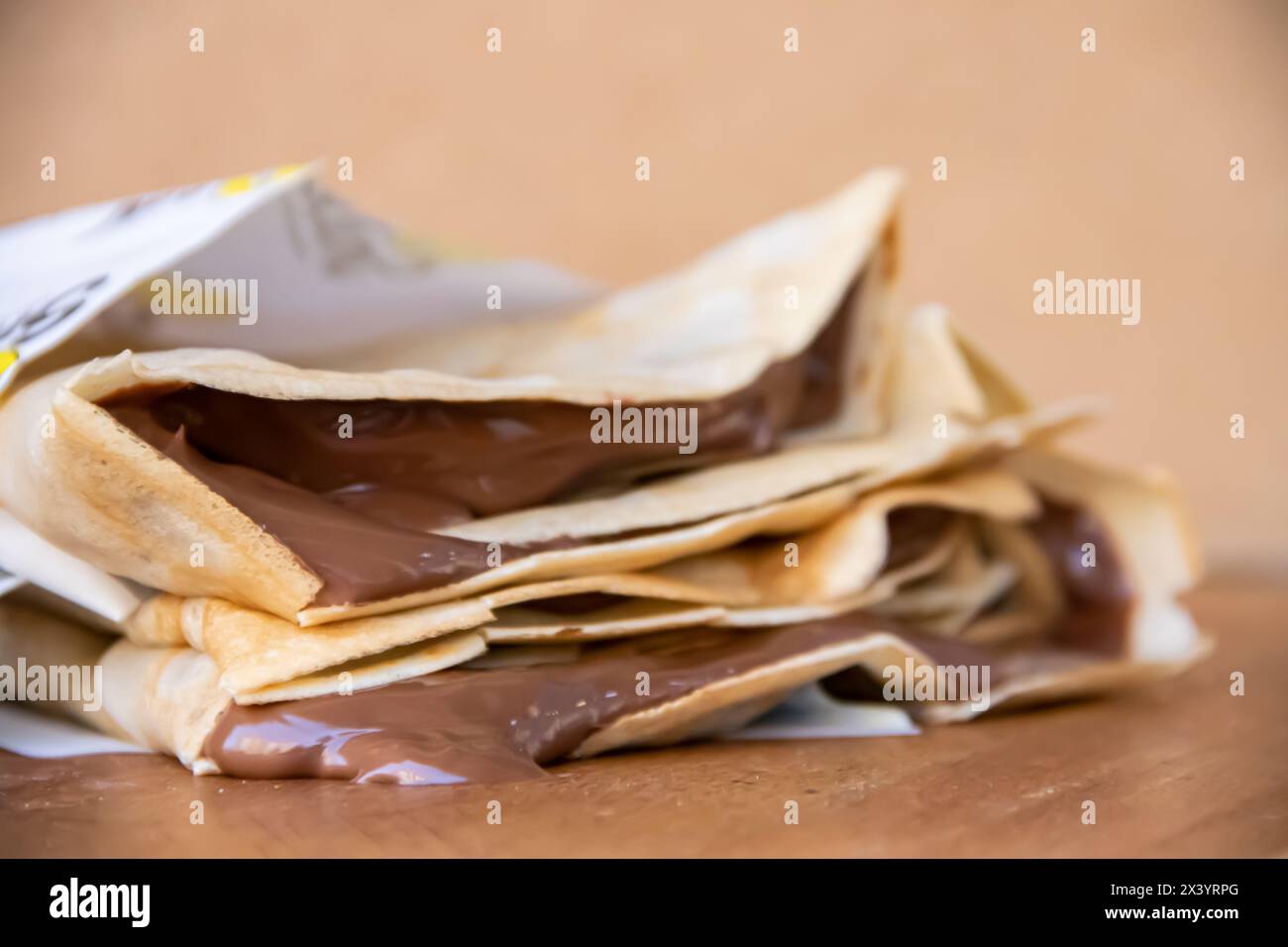 Bunch of home made pancakes filled with dripping melted hot chocolate, chocolate drips down the wooden table out of the pancakes Stock Photo