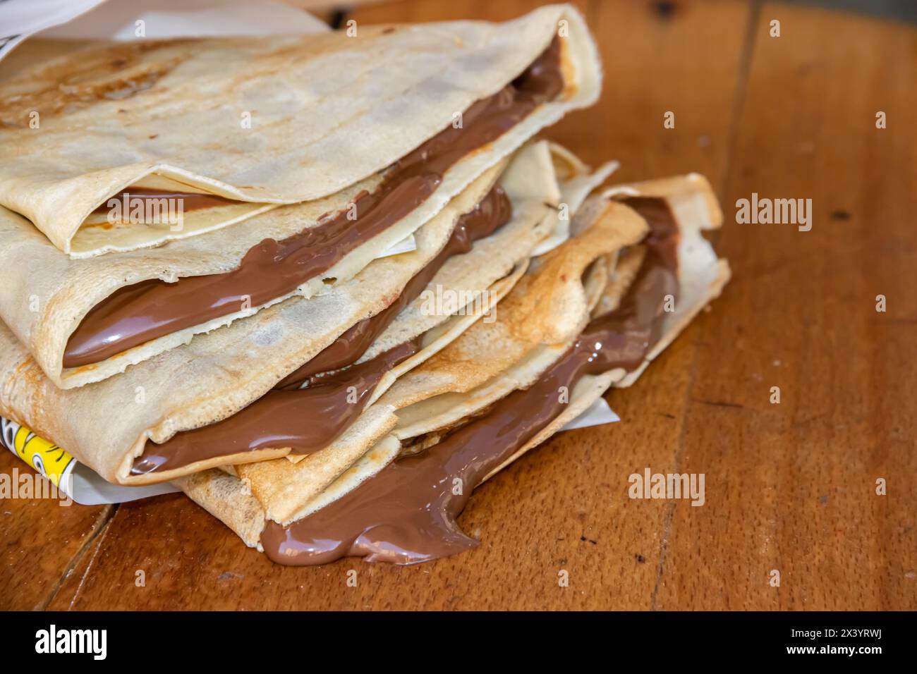Bunch of home made pancakes filled with dripping melted hot chocolate, chocolate drips down the wooden table out of the pancakes Stock Photo