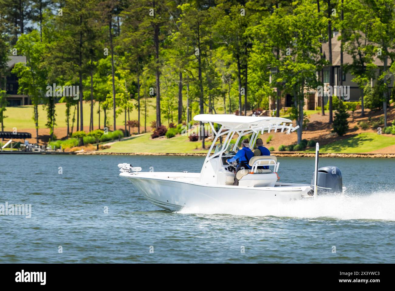 Boaters on fishing boat enjoy summer day on the lake. Power boat cruising on freshwater lake. Stock Photo