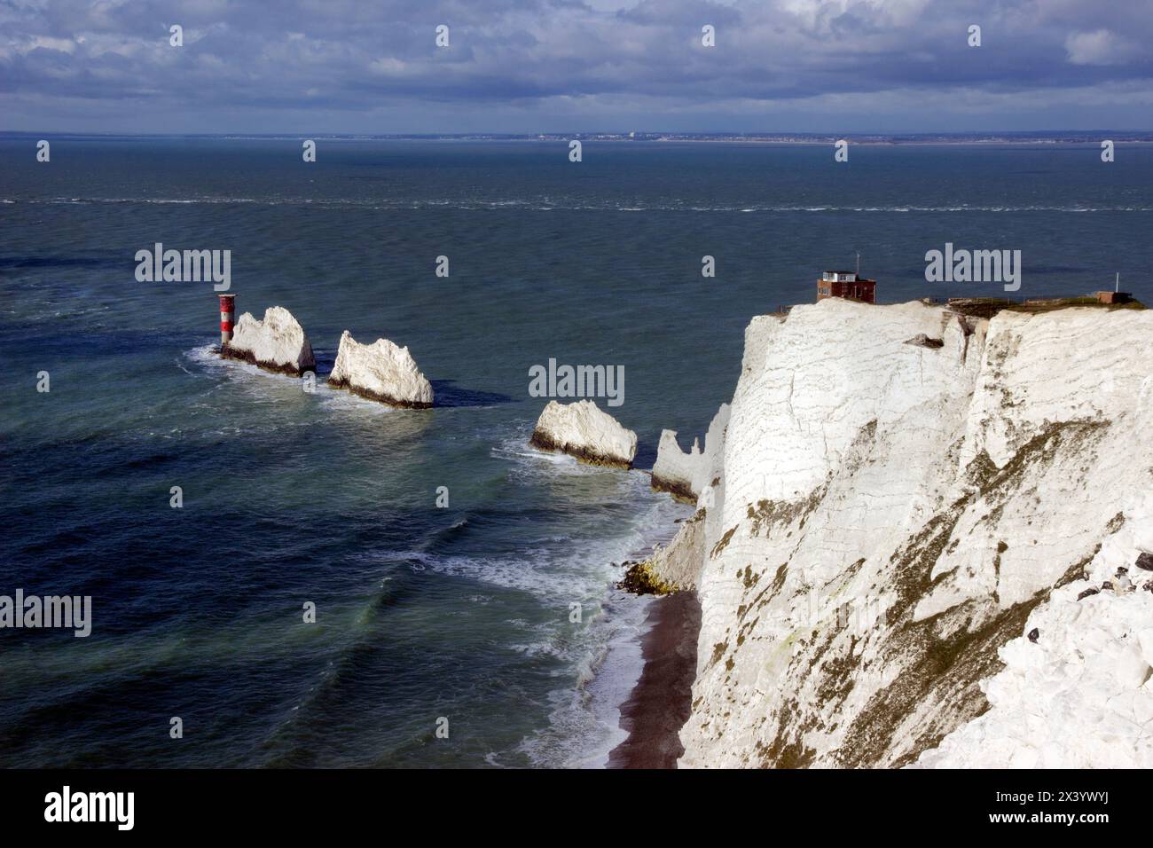The Needles, a row of three chalk stacks off the west coast of the Isle of Wight, rising about 30m out of the sea, with the Needles Lighthouse beyond Stock Photo