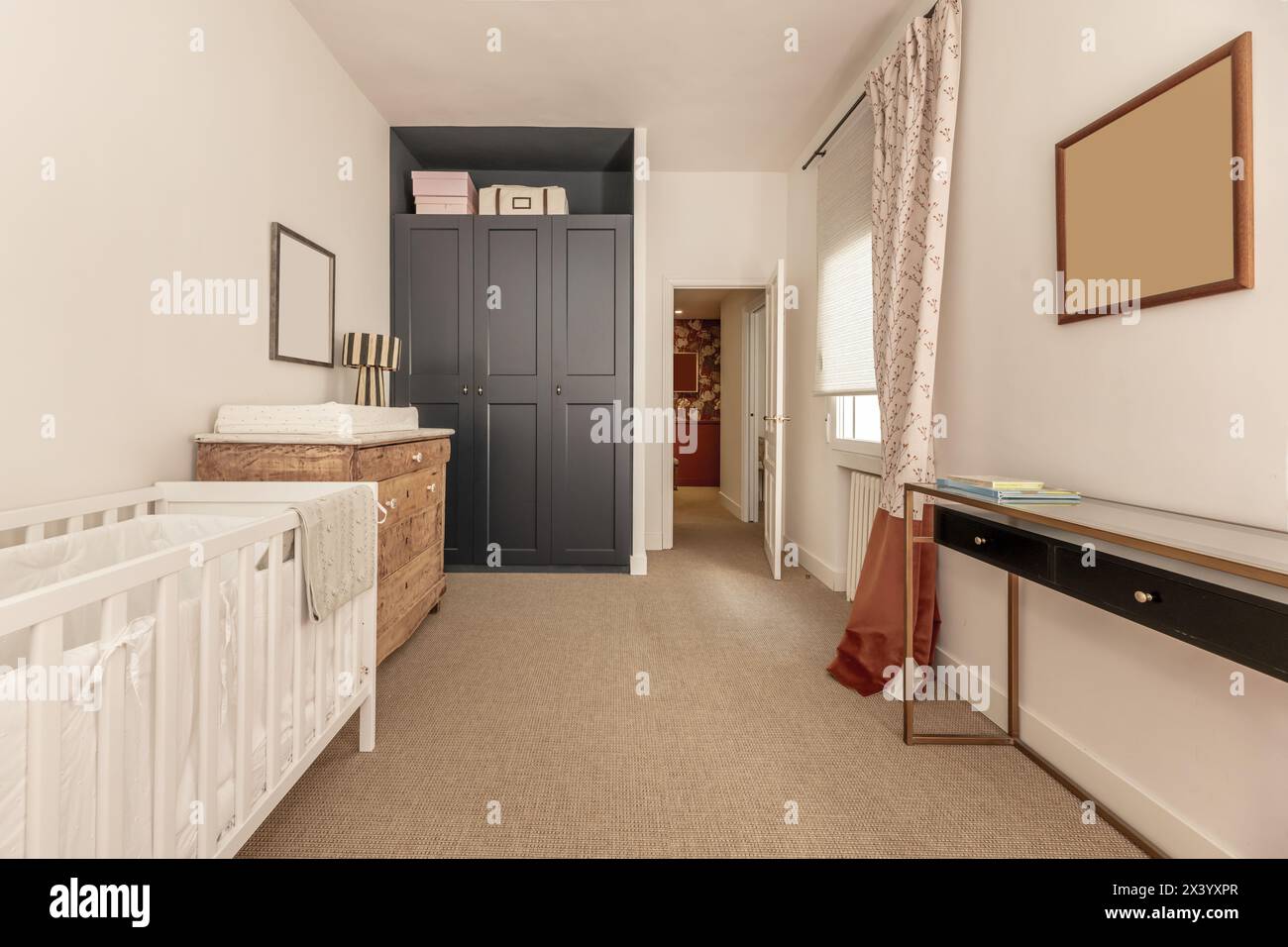 Children's bedroom with white wooden crib, blue wooden built-in wardrobe, vegetal fiber carpet floors and antique wooden appliances Stock Photo