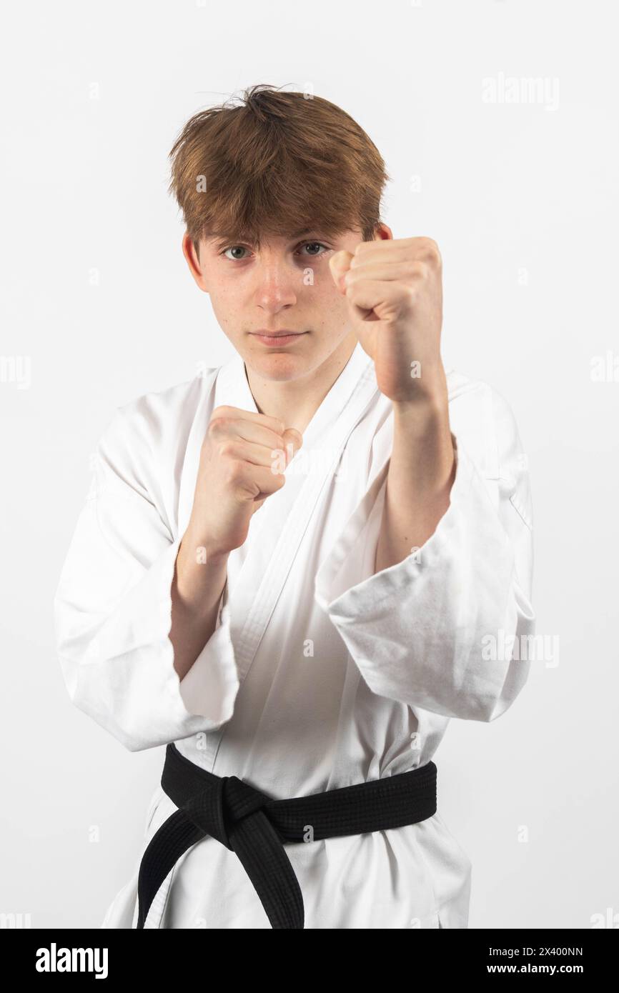 A 15 year old Karate Blackbelt boy, wearing A Gi with his guard raised Stock Photo