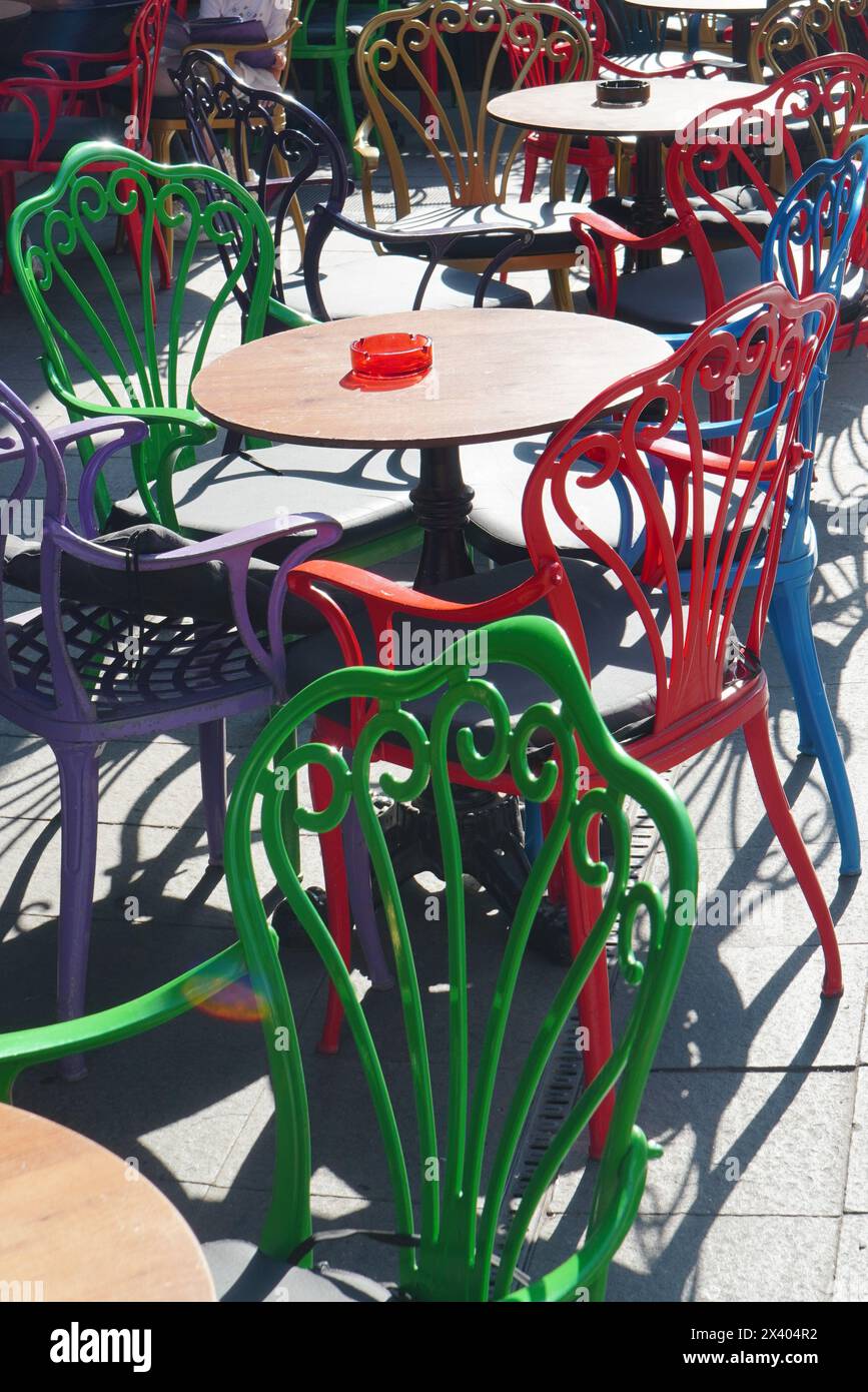 Street cafe with round tables and backrest chairs of different colors in center of Bucharest on sunny day Stock Photo