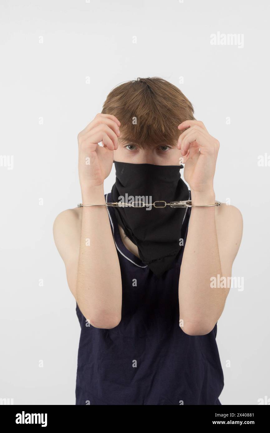 A Teenage Boy Wearing a Mask, Arrested in Handcuffs Stock Photo