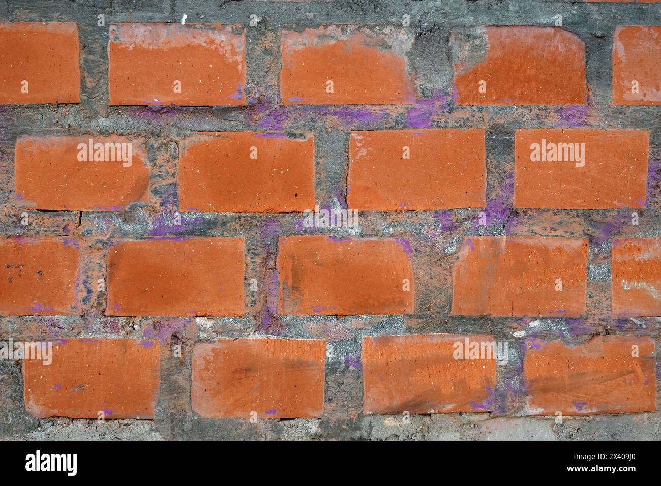 Red bricks in concrete wall with as background front view close up horizontal view Stock Photo