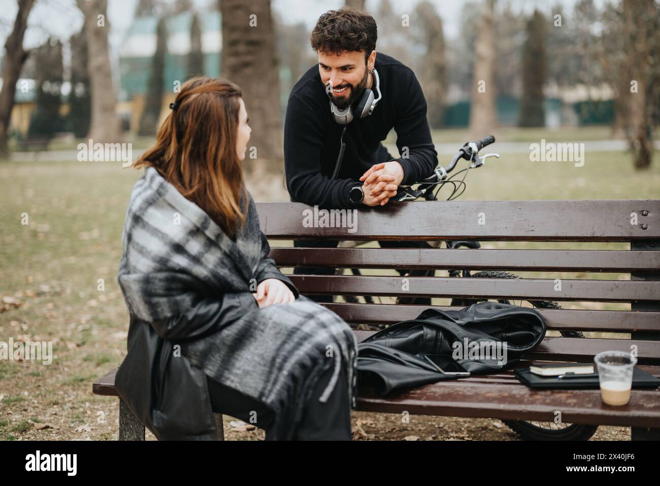 Friendly conversation between man and woman at park bench with bicycle ...