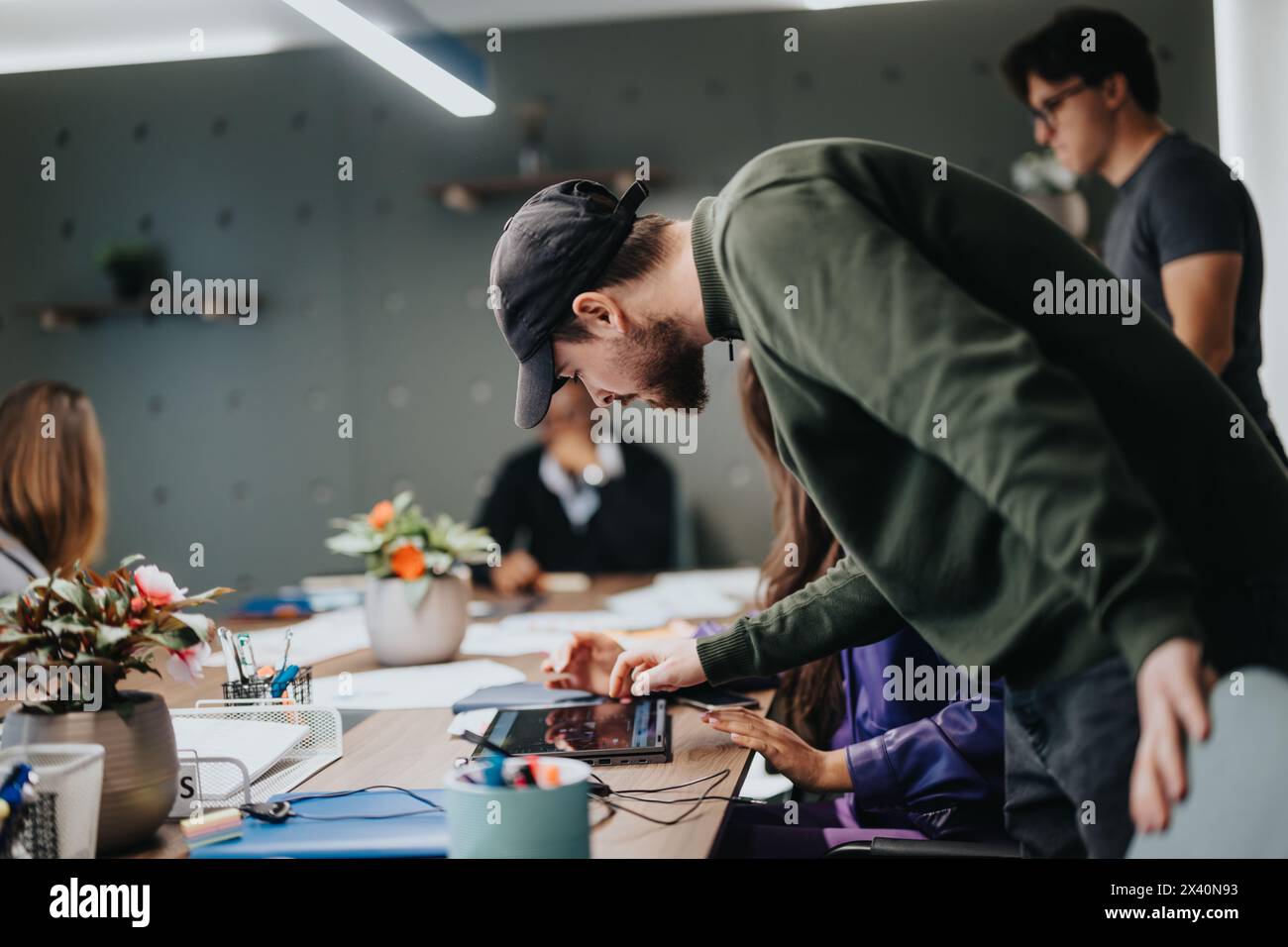 Creative team collaborating in bustling office environment, focus on technology and innovation Stock Photo