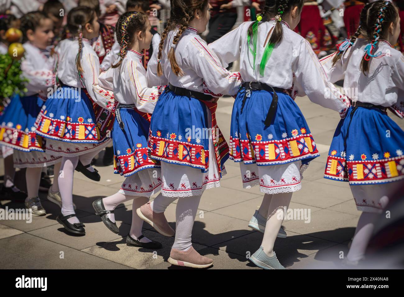 School age girls in traditional Bulgarian costumes dancing folk dance, back view Stock Photo