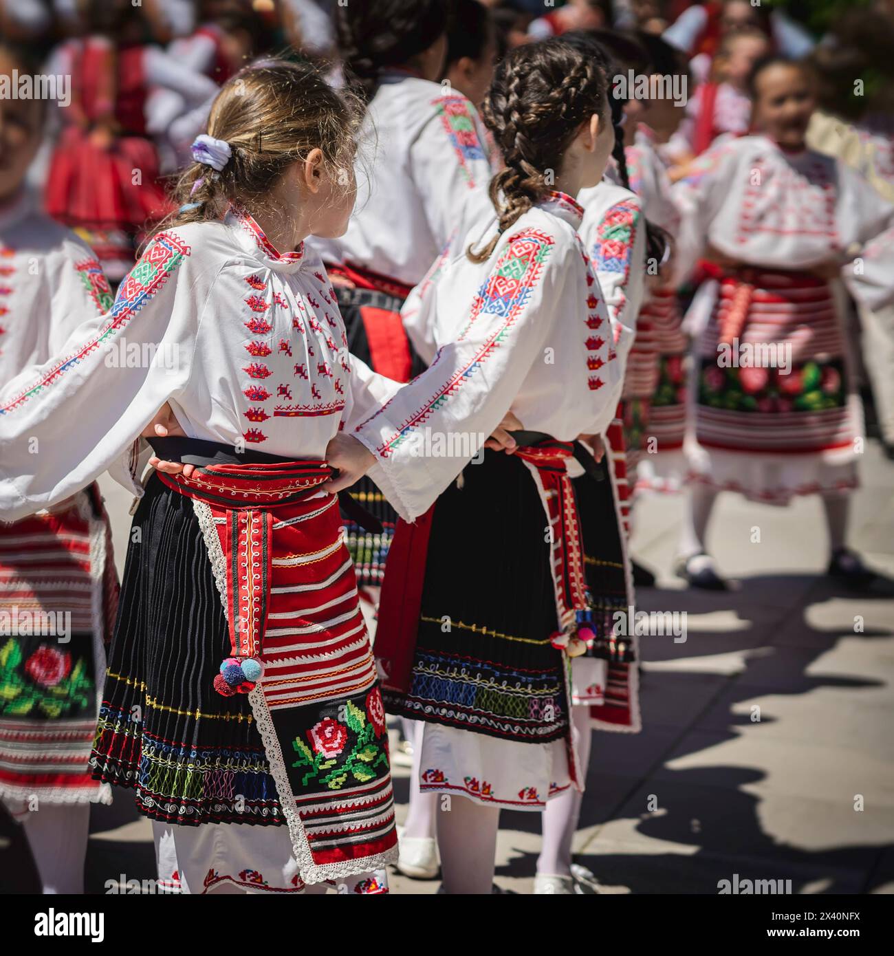 Girls in traditional costumes dance Bulgarian folk dances, summer sunny day Stock Photo