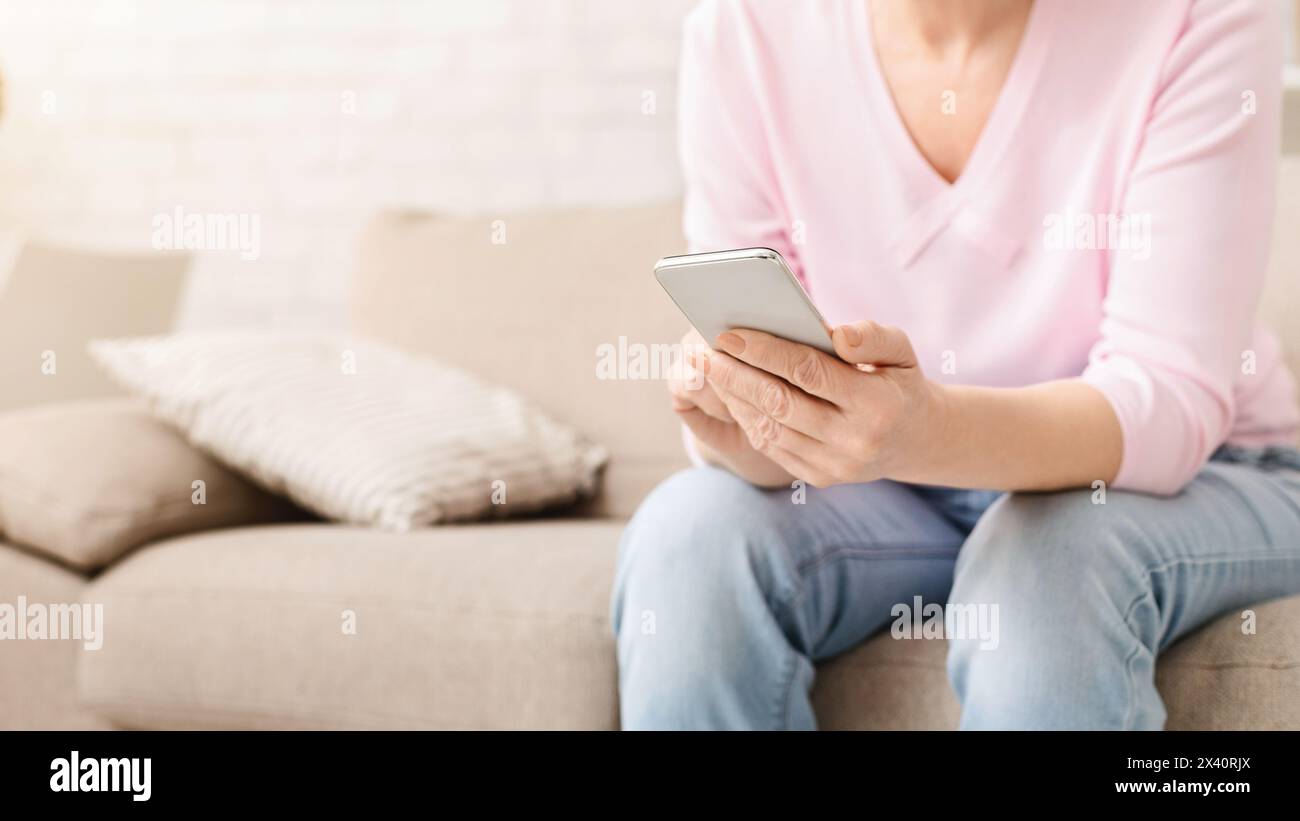 Cheerful aged woman using her smartphone at home Stock Photo