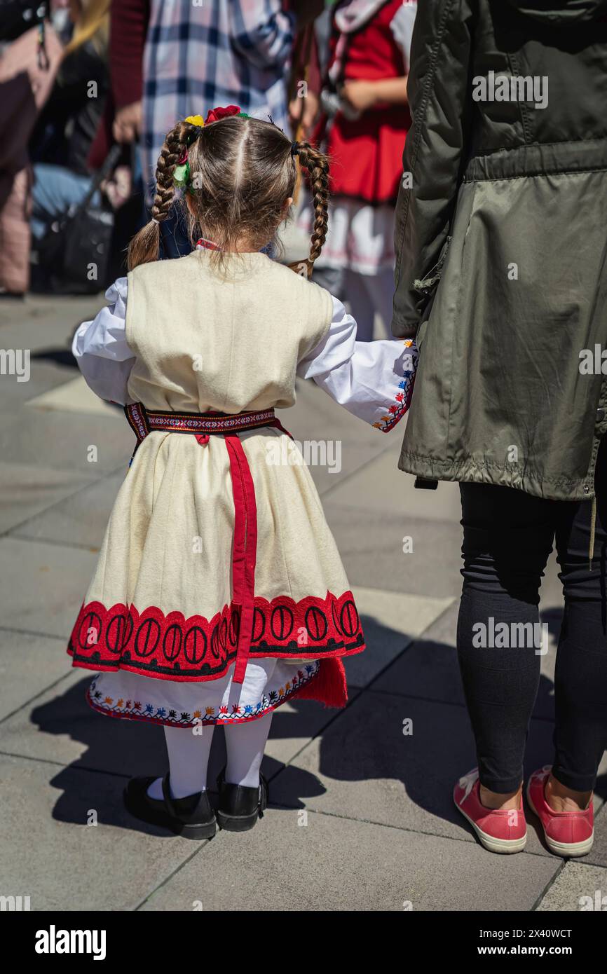 Little girl in traditional Bulgarian costume at the folk festival outdoors back view Stock Photo