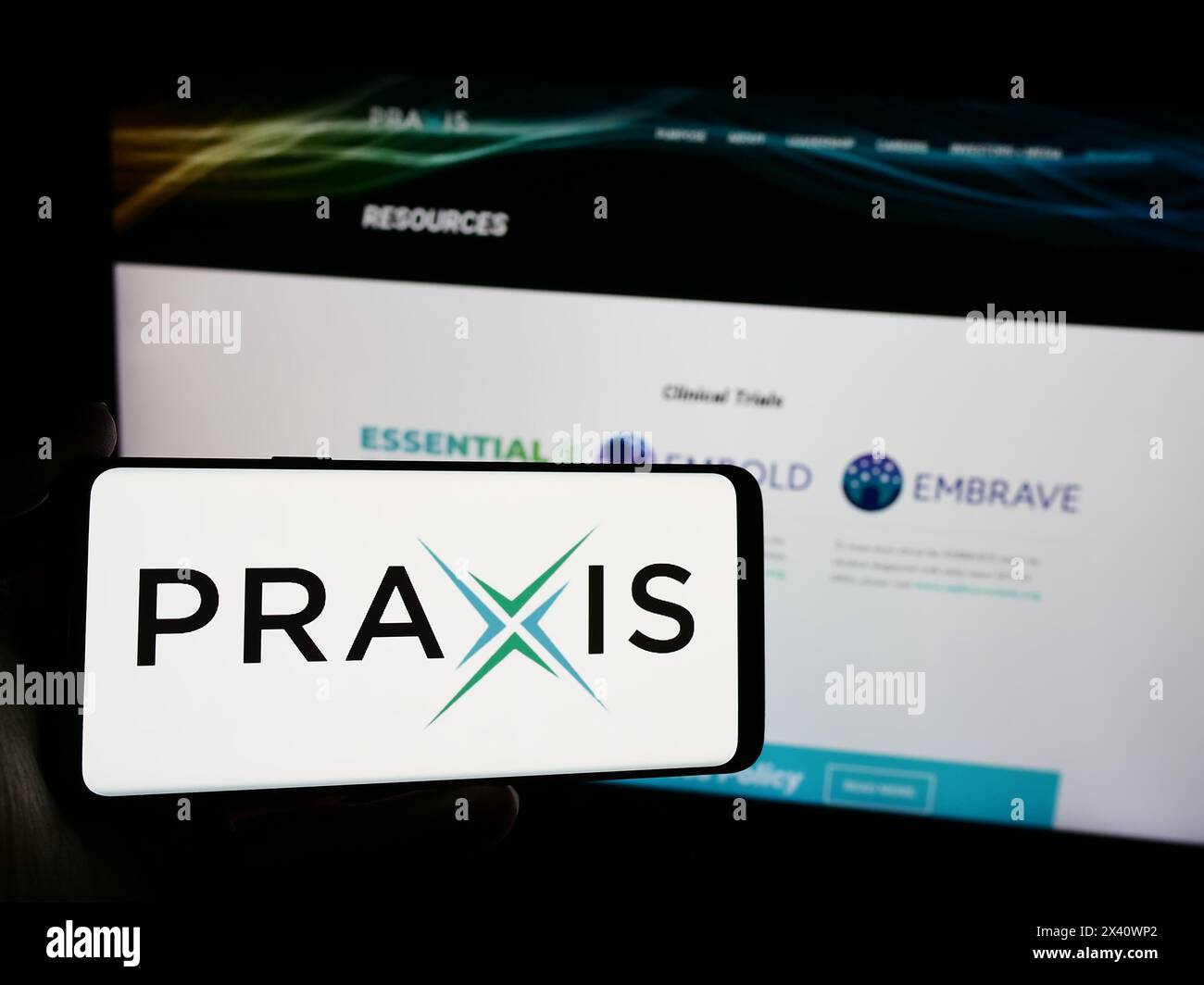 Person holding mobile phone with logo of American biopharma company Praxis Precision Medicines Inc. in front of web page. Focus on phone display. Stock Photo