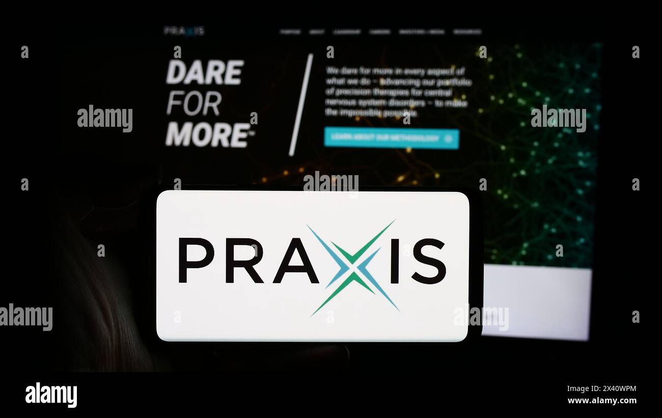 Person holding cellphone with logo of US biopharma company Praxis Precision Medicines Inc. in front of business webpage. Focus on phone display. Stock Photo