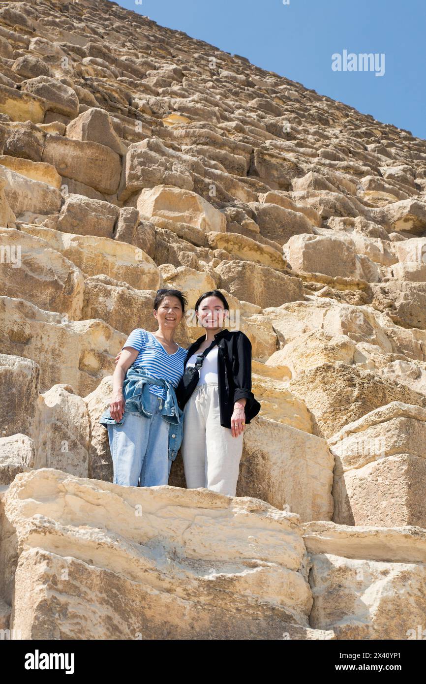 Mother and daughter female tourists standing in front of the Great Pyramid of Giza;  Giza, Egypt Stock Photo