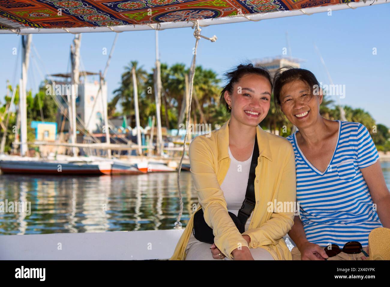 Mother and daughter tourists taking a felucca ride on the Nile to the tombs of the Nobles in Aswan, Egypt; Aswan, Egypt Stock Photo