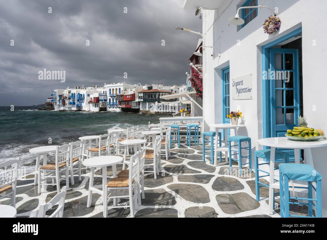 Seating on an outdoor waterfront restaurant patio on the island of Mykonos, with a view of the fishing houses in Little Venice; Mykonos, Greece Stock Photo