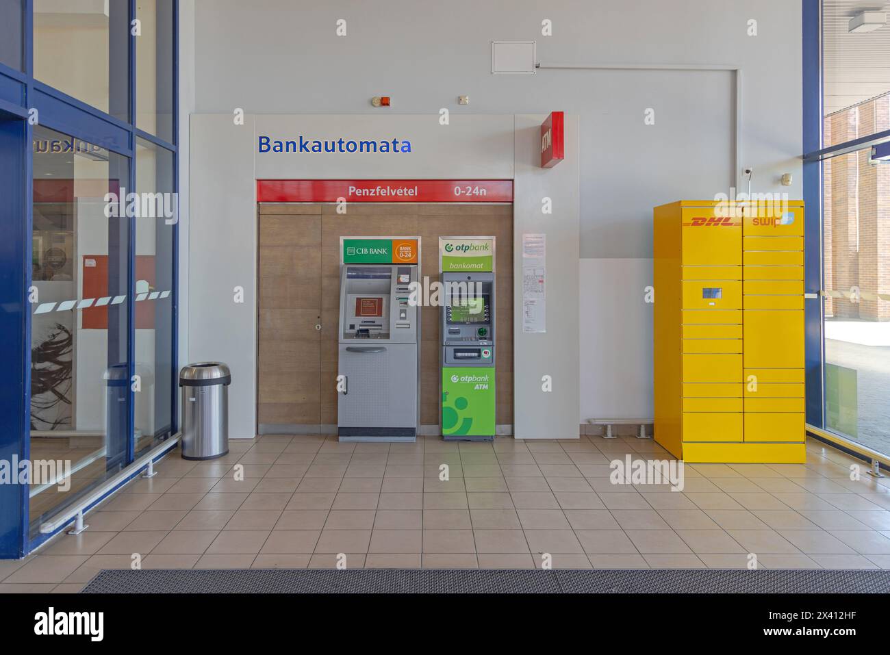 Szeged, Hungary - August 01, 2022: Atm Cib Bank Otp Bankomat and Yellow DHL Locker Swip Box in Tesco Supermarket and Shopping Mall Located in Sunshine Stock Photo