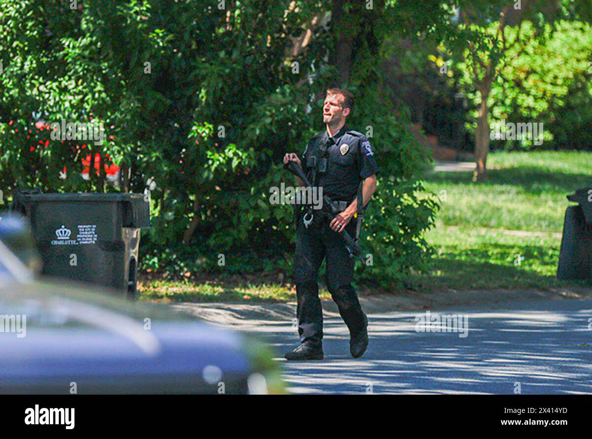 A Charlotte Mecklenburg police officer carries a gun as he walks in the neighborhood where an officer-involved shooting took place in Charlotte, N.C., Monday, April 29, 2024. Police in North Carolina say numerous law enforcement officers conducting a task force operation have been struck by gunfire in Charlotte. (AP Photo/Nell Redmond) Stock Photo