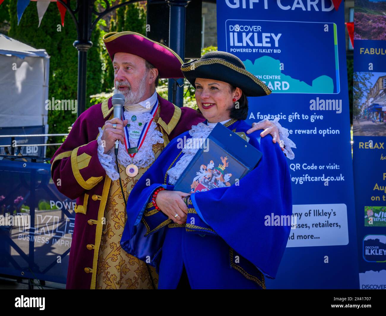Town criers standing together side by side (lady crier & 1st first prize award winner, colourful criers' livery) - Ilkley, West Yorkshire, England UK. Stock Photo