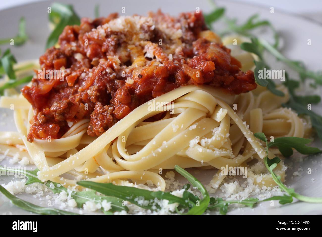 Traditional Bolognese Linguine with Shaved Parmesan and Fresh Arugula Stock Photo