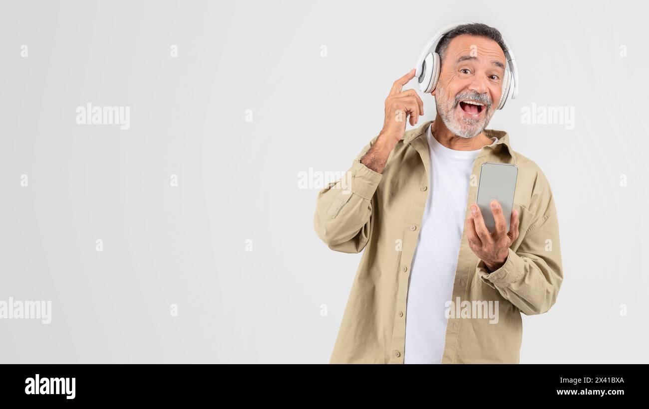 Man Holding Cell Phone And Using Headphones Stock Photo
