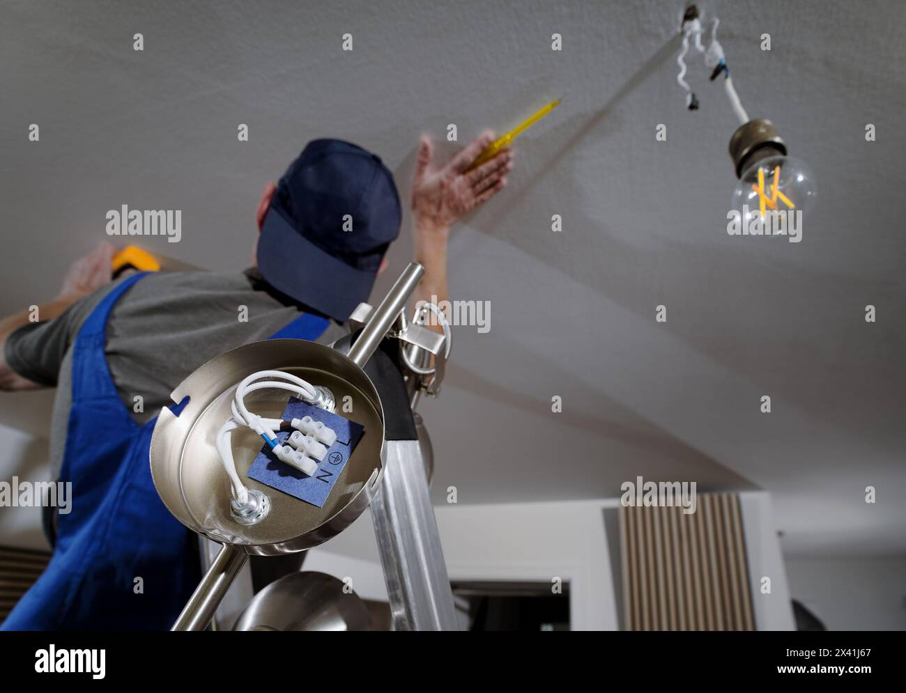 Electrical engineer fitter electrician installing ceiling light lamp