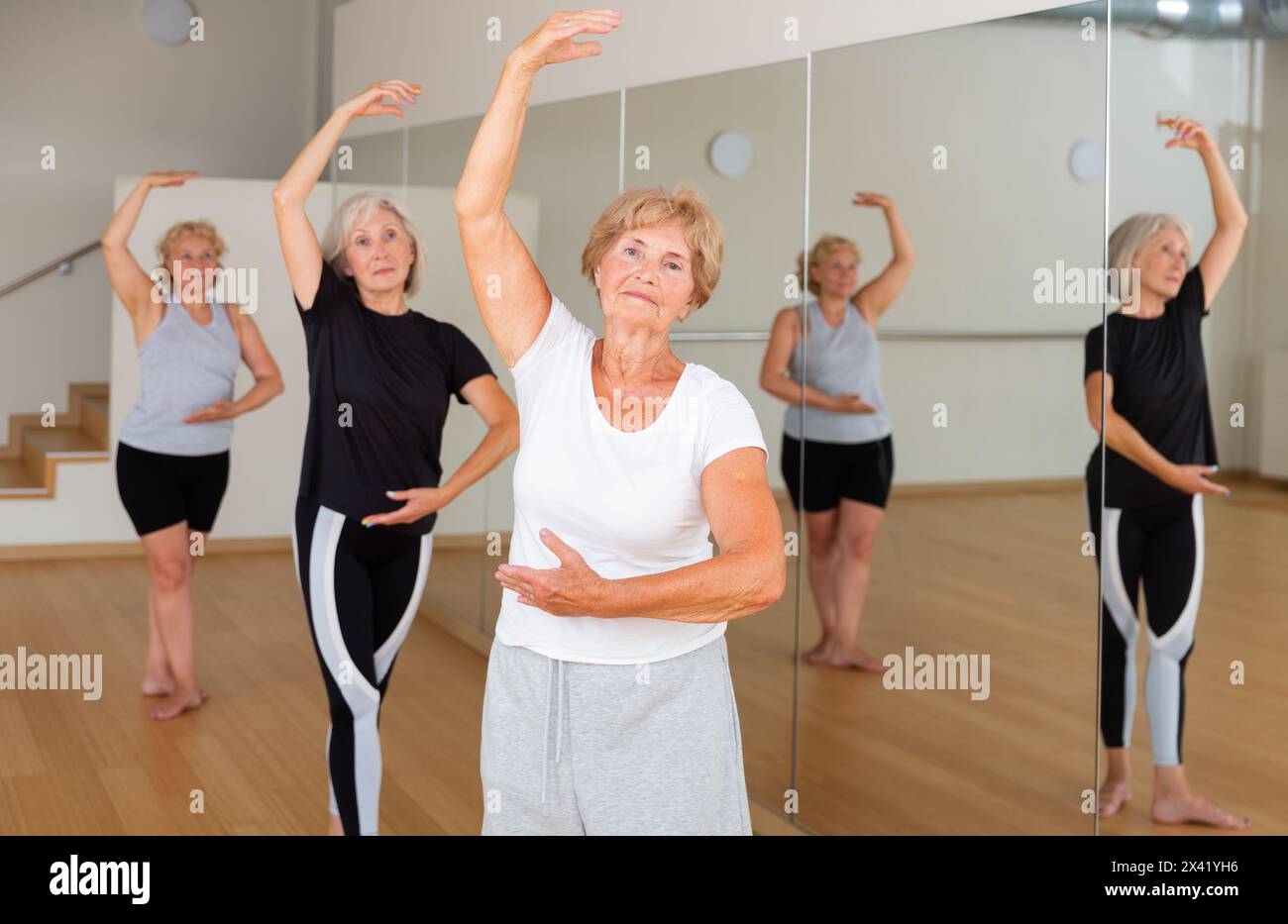 Senior lady learning classic dance moves during group class Stock Photo