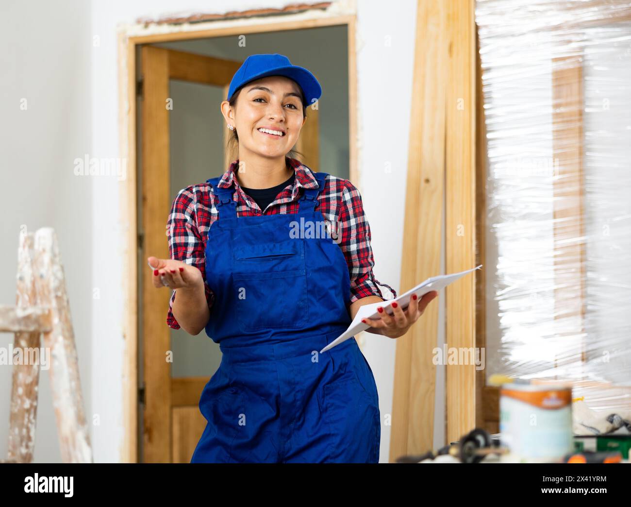 Positive woman builder with documents in apartment Stock Photo