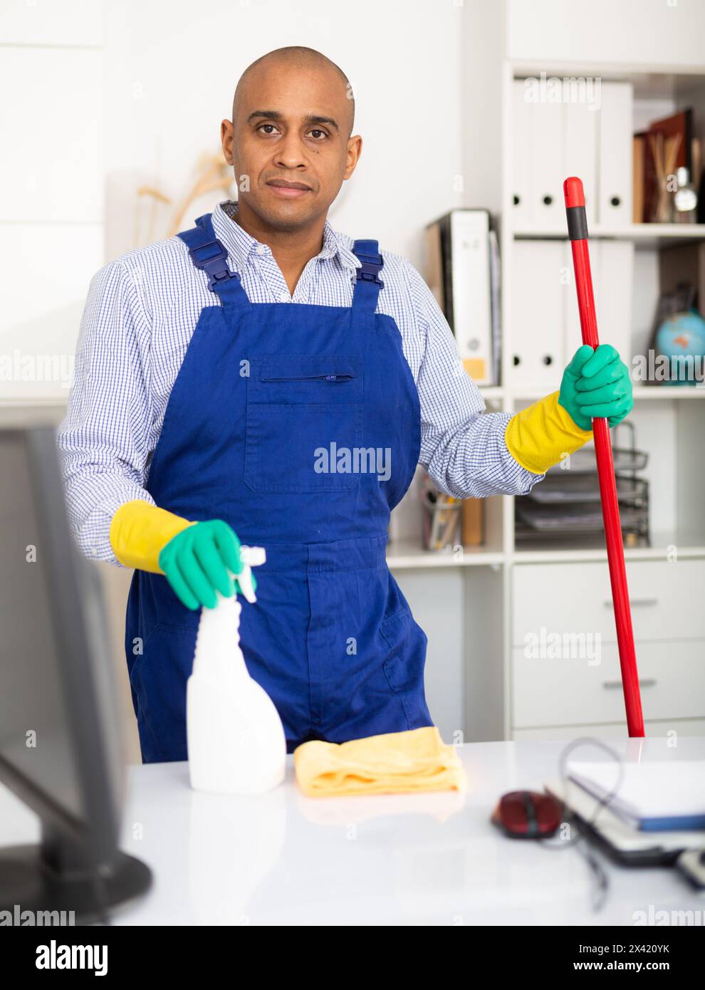 Portrait of male worker with broom cleaning office Stock Photo