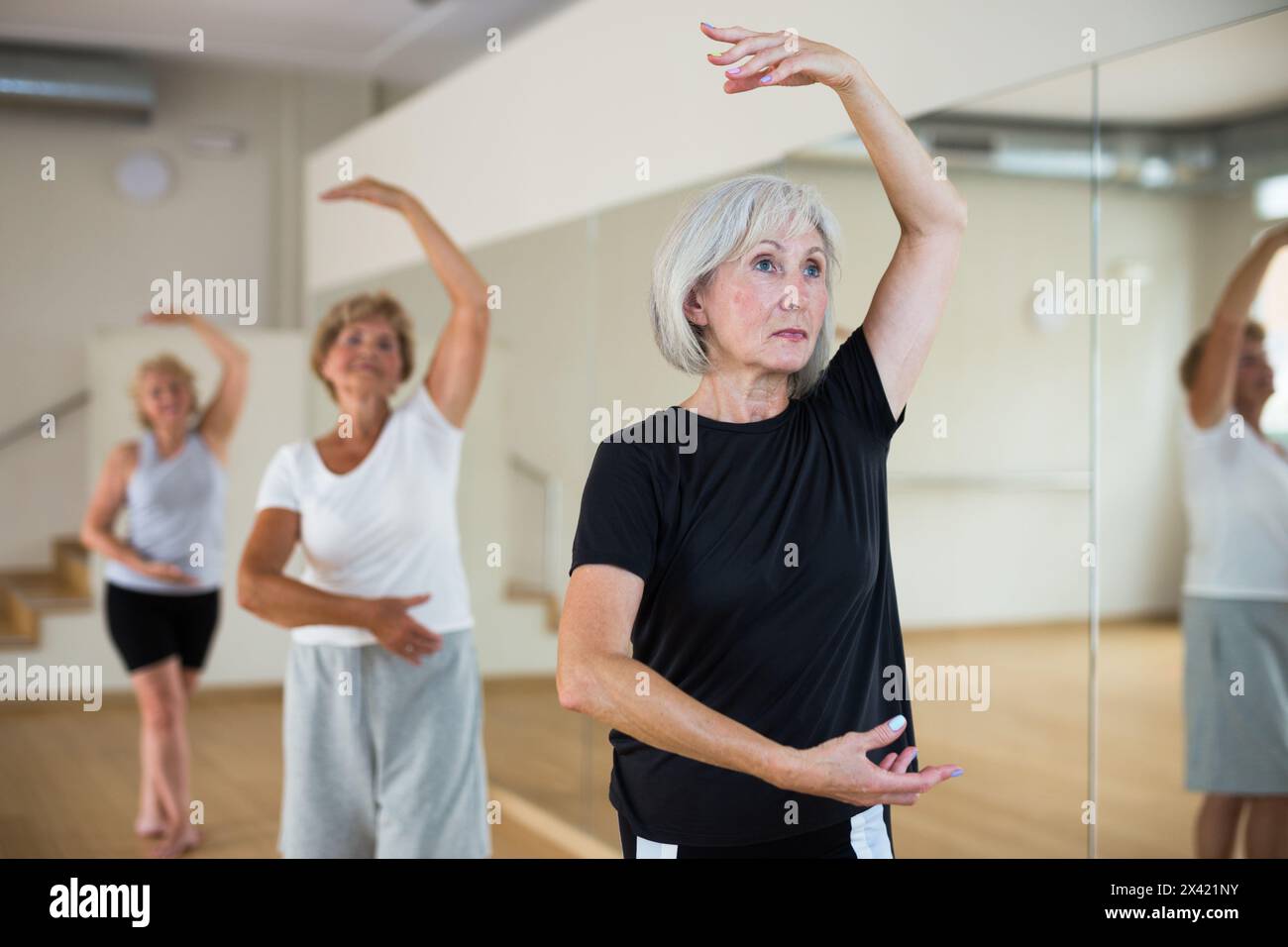 Mature woman learning classical ballet technique in choreography class Stock Photo