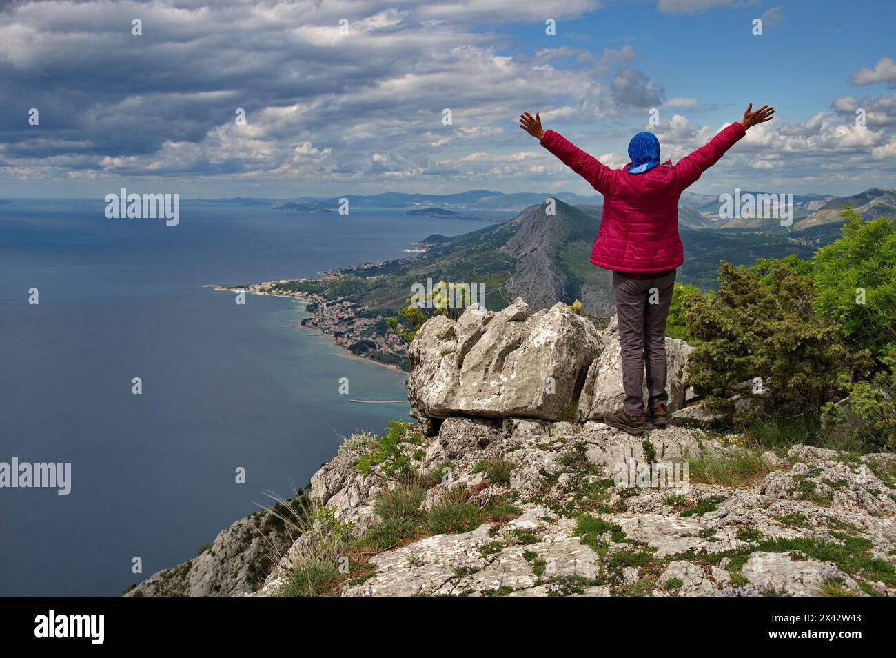 Rear view of senior woman hiking in rocky landscape with beautiful view of Adriatic sea Stock Photo
