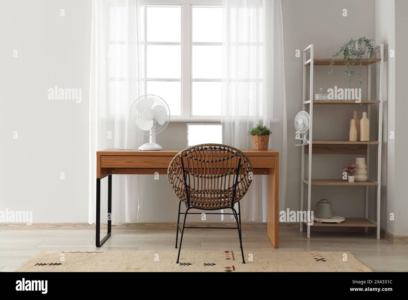 Comfortable workspace with modern laptop and electric fan on wooden ...