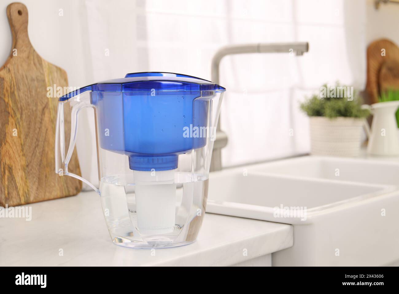 Water filter jug on white countertop in kitchen, space for text Stock Photo