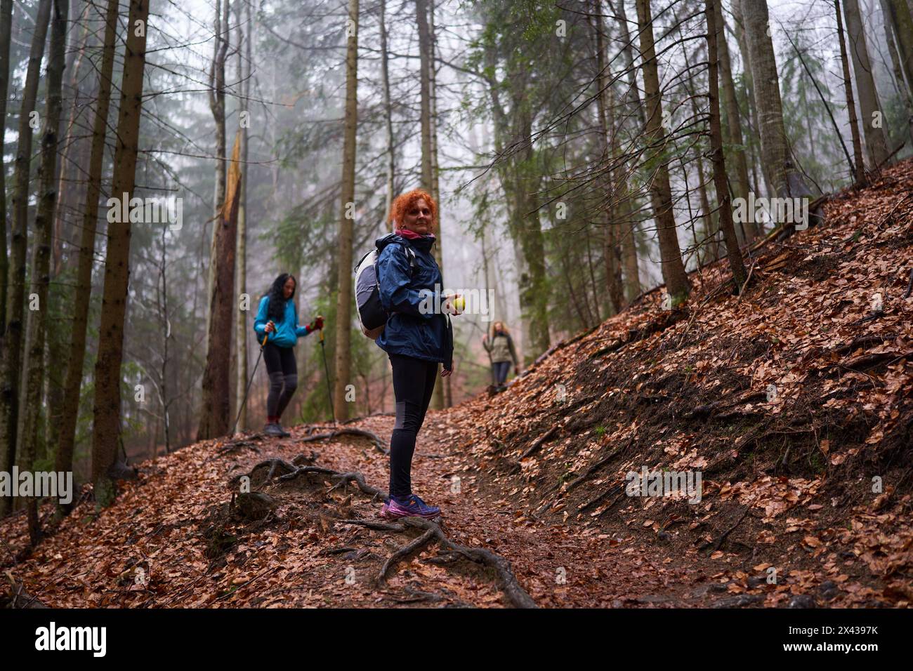 Women with backpacks hiking on a rainy day in the mountains Stock Photo