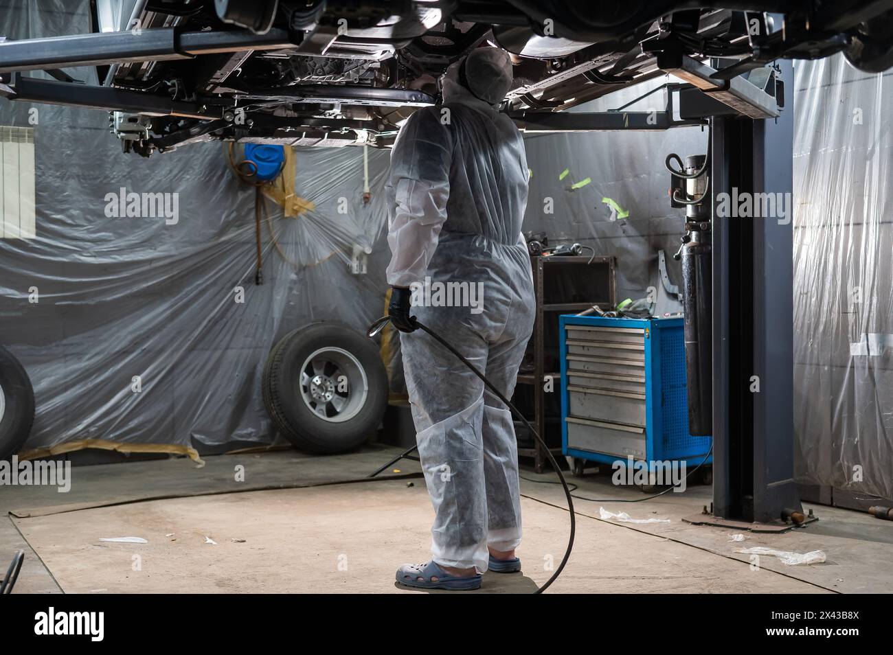 The master sprays an anti-corrosion compound on the bottom of the car ...