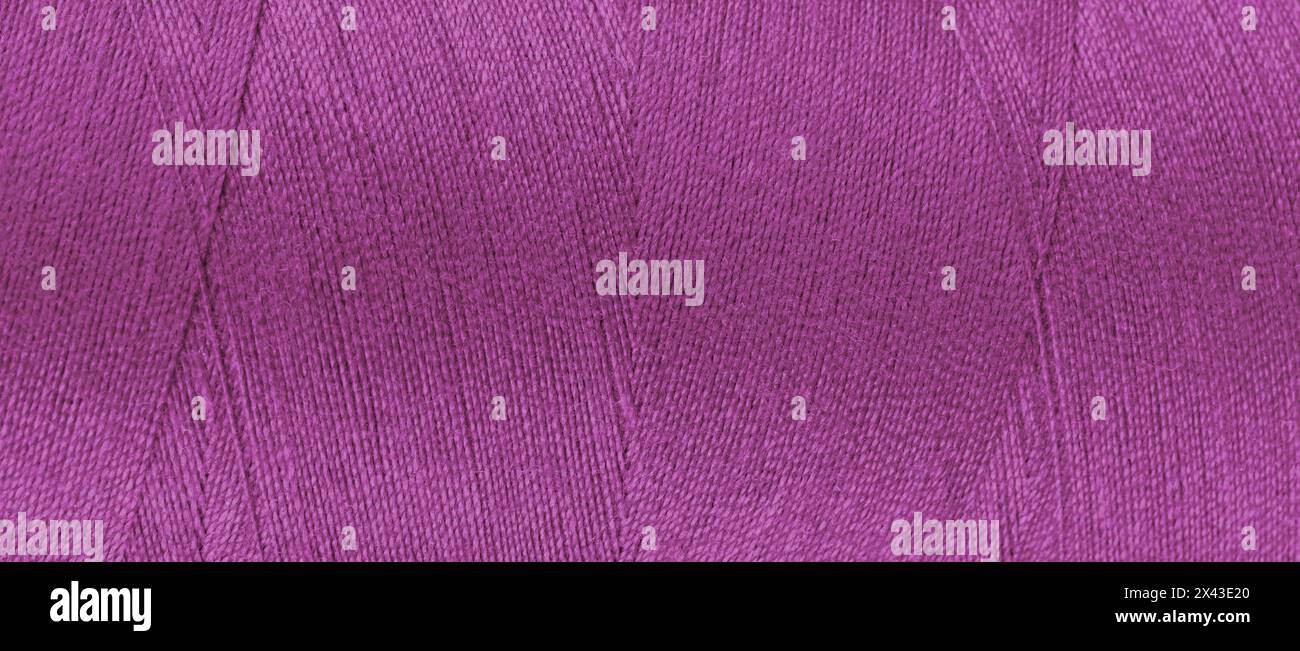 Texture of pink color threads in spool close up, macro. Wide banner, header of sewing threads bobbin abstract background, wallpaper, backdrop. Stock Photo
