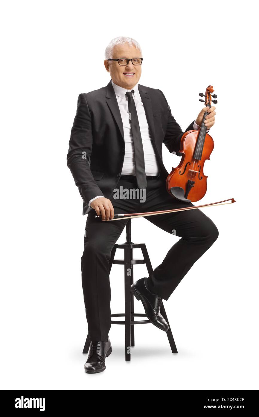Mature man sitting on a chair and playing a violin isolated on white ...