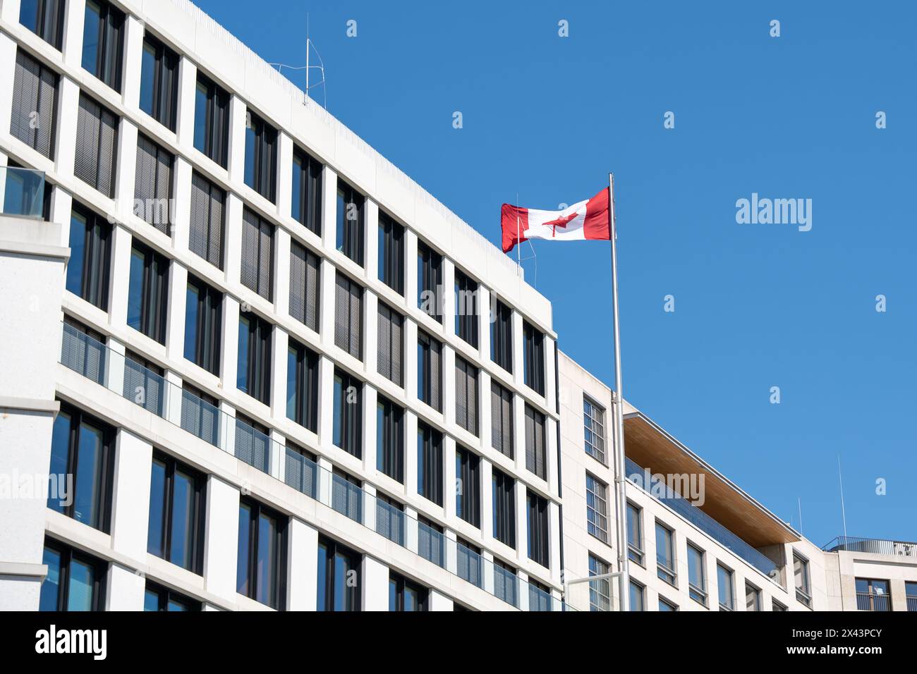 Waving Canadian flag against a blue sky. Canadian flag on the roof of the building. Stock Photo